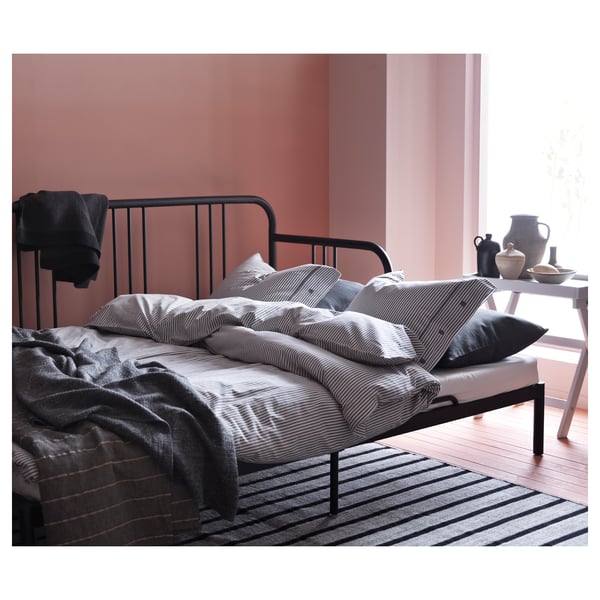 Black fyrsdal daybed with steel frame, foam mattress, striped pillows, pink walls, striped rug