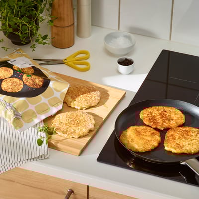 Kitchen counter with GÅNGLÅT pancakes in packaging and pan. Cutting board, scissors, ingredients visible.