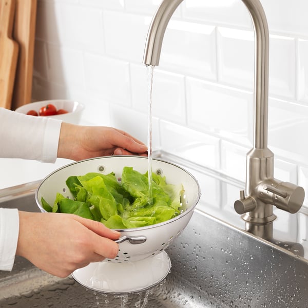 Washing lettuce in colander under kitchen tap.