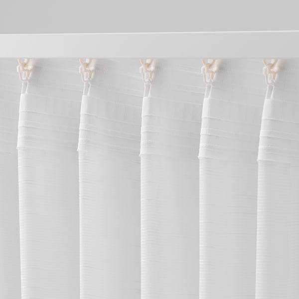 Sheer white curtains hanging, allowing light while offering privacy, with visible curtain hooks at the top.