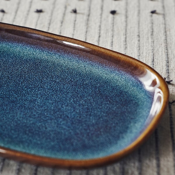 Blue plate with gold rim on striped cloth.