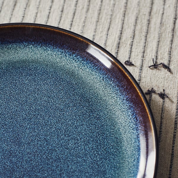 Blue plate on striped cloth.