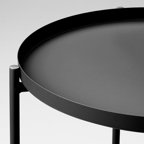 Modern round tray table with sleek black finish. Durable powder-coated steel surface, supported by sturdy metal legs.