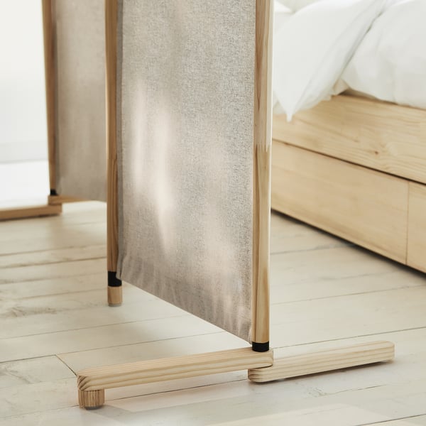 Light wood room divider in neutral fabric, dividing bedroom with bed and floor.
