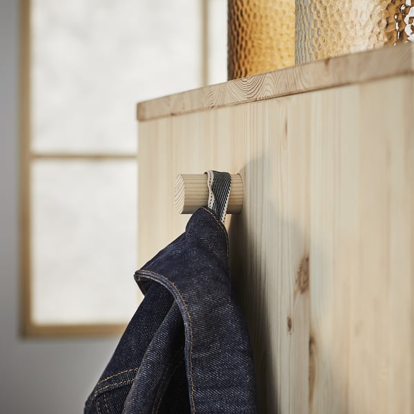 Wooden coat hook with denim jacket. Visible grain, light panel.