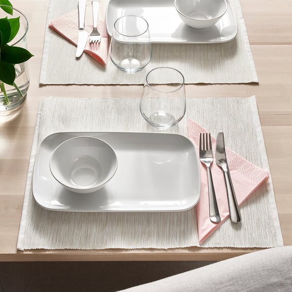 Elegant table setting with white dinnerware, cutlery, and glasses, ready for dining.