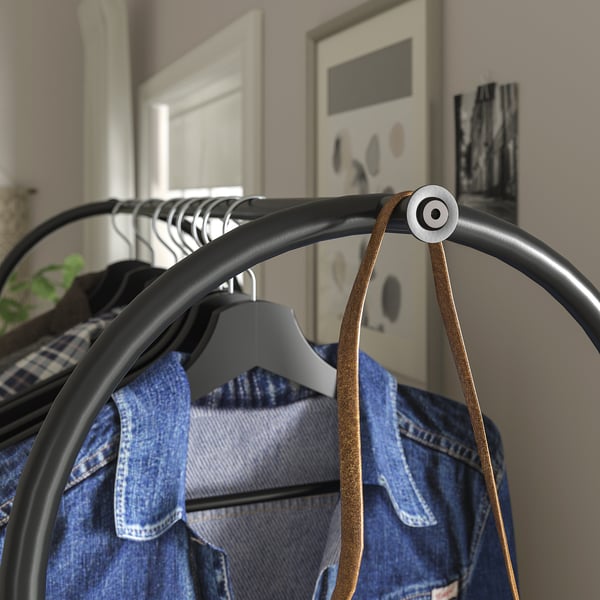 Black metal clothes rack with adjustable feet, holding blue jeans with grey hangers.