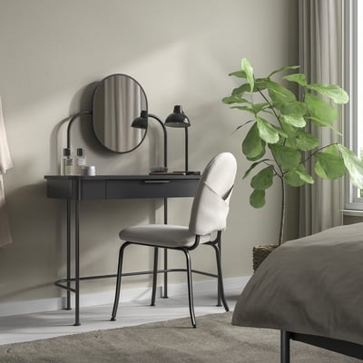 Black GRÅFJÄLLET dressing table with mirror, next to plant and chair, minimalist.