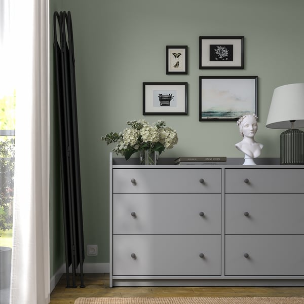 Grey dresser with three white hydrangeas, art, and lamp; green wall with gallery 3 piece wall art.