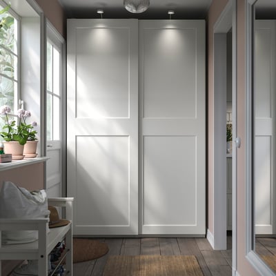 Modern room with white sliding closet doors, beveled edges, and natural wood floor.