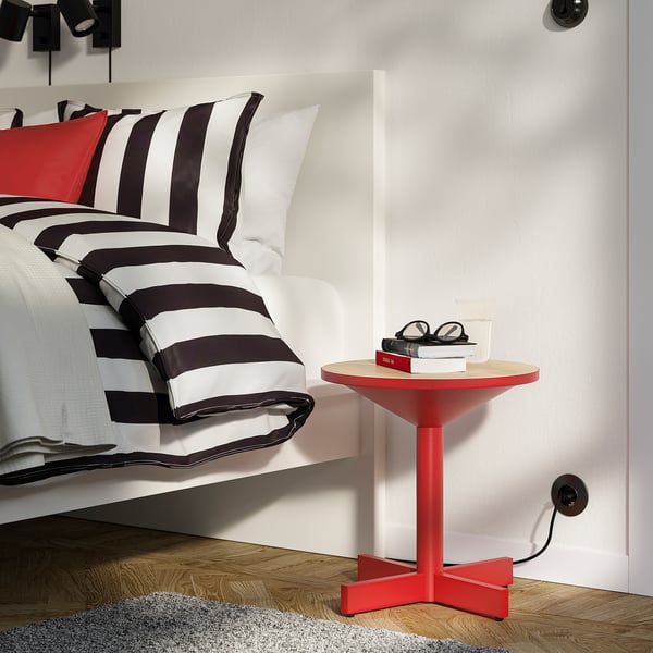 Red GRIMSARBO bedside table with wooden top and metal legs, ideal for small spaces.
