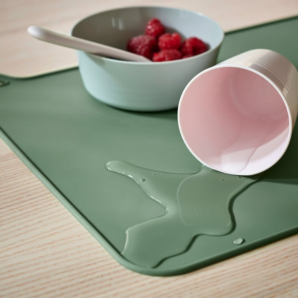 Green silicone place mat with cat design. It protects tables from spills and keeps its place.