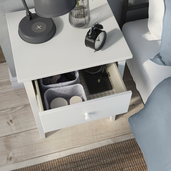 GULLABERG bedside table with open drawer, alarm clock, vase, lamp, and wireless charger on rug, beside bed.