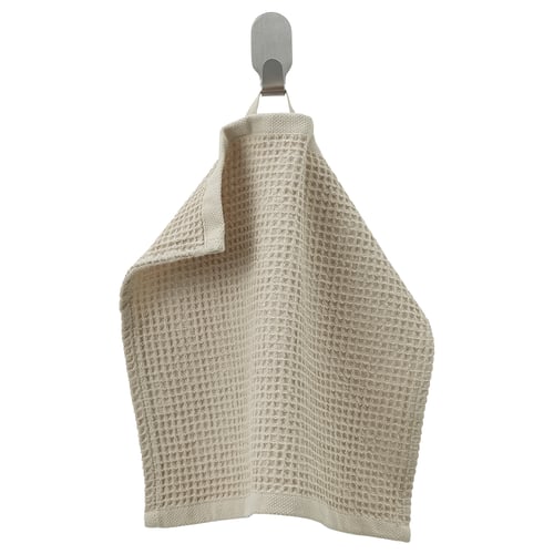 A beige-colored GULLDYNA towel hanging on a hook. The towel is made of recycled cotton, a textured weave, and is rectangular in shape.