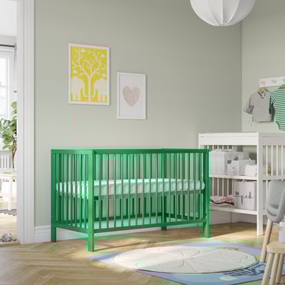 Bright green GULLIVER baby cot, square with spindles, fits well in cosy nursery, surrounded by decor.