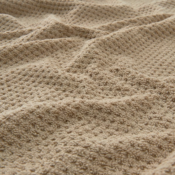 Beige, textured cotton towel, visually soft and fluffy, displaying intricate weave pattern.