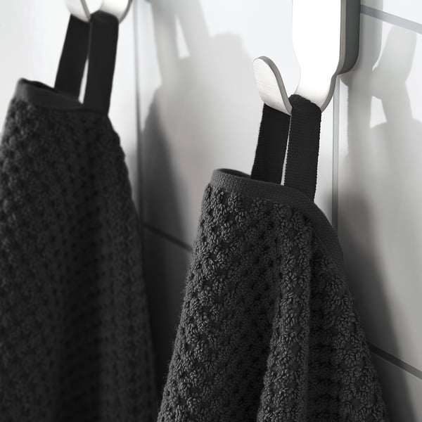 Black towels hang on hooks. One has straps, both appear soft and fluffy.