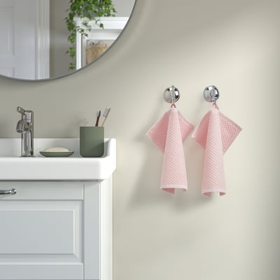 Bathroom with pink GULVIAL towels on chrome hooks by sink.