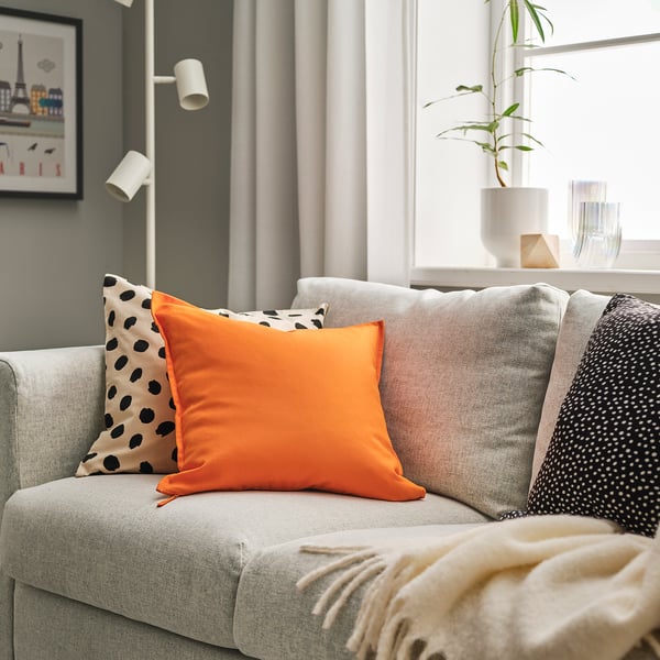 Grey sofa with bright orange GURLI cushions - one solid, one polka dot.