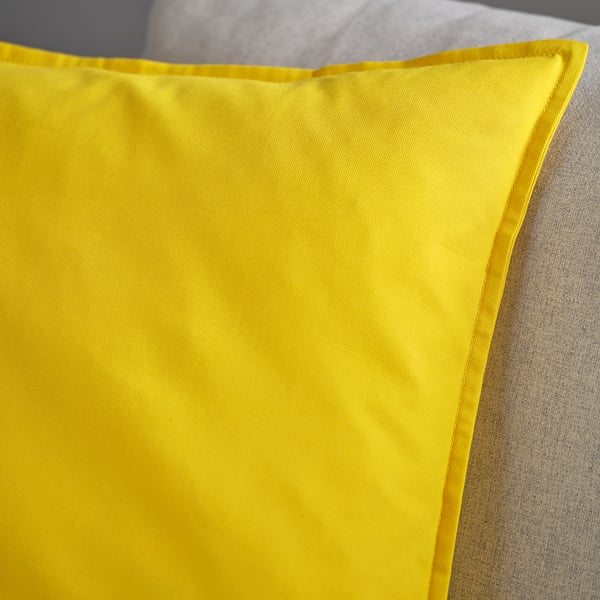 Bright yellow cushion cover on fabric, showing smooth texture and well-sewn stitching details.