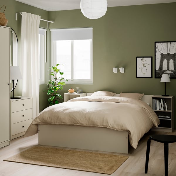 Modern white GURSKEN chest in bedroom, ideal for small spaces. Tall, next to window with lamp and plant.