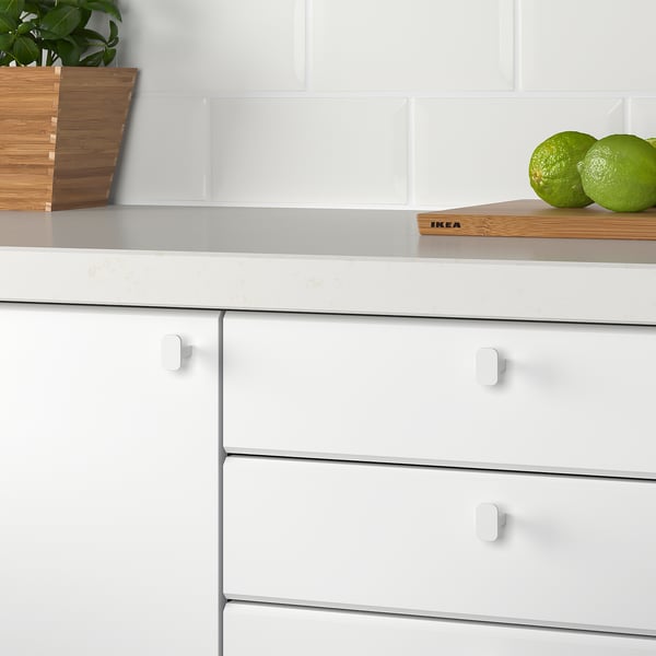 White kitchen knobs on cabinet drawers, smooth to touch.