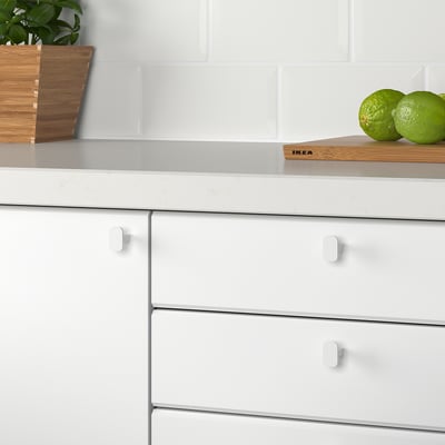 White kitchen knobs on cabinet drawers, smooth to touch.