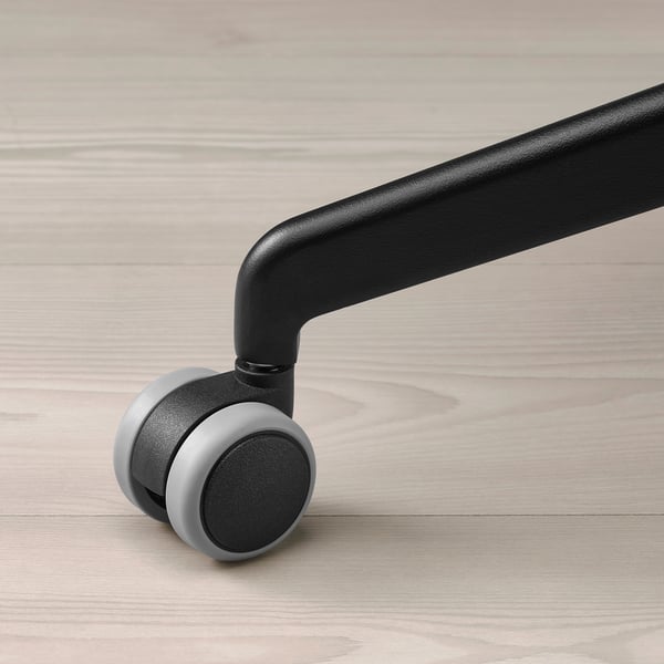 Black office chair wheel, smooth and sturdy. Mounted on wooden floor, high-quality feel.