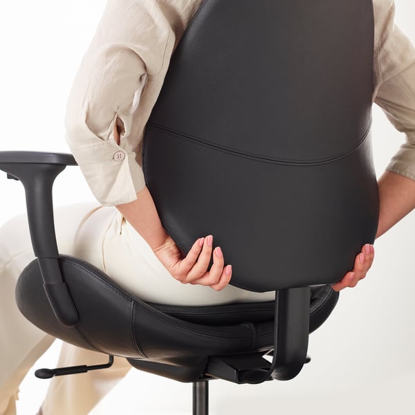 Person sitting in an ergonomic chair, adjusting back support.