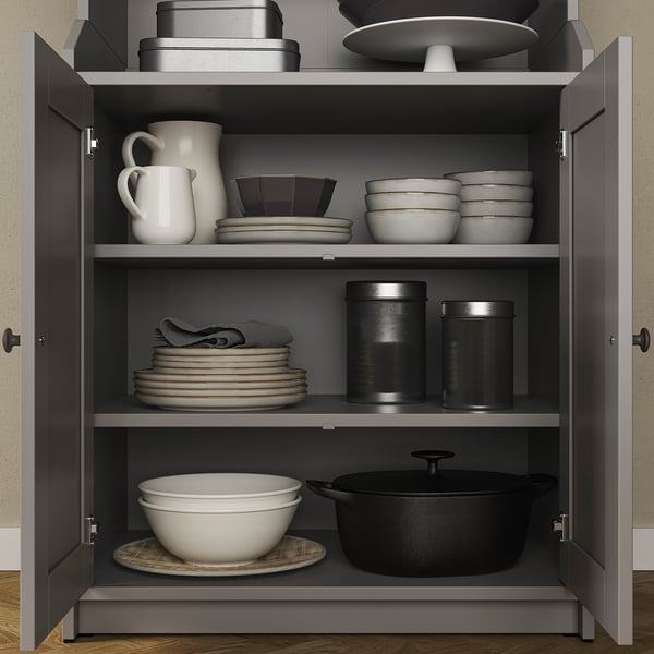 HAUGA grey kitchen cabinet with white dishes, bowls, jug, pots, and black containers.