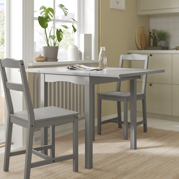 Modern grey wooden dining set in kitchen, featuring rectangular drop-leaf table and two matching chairs with simple design and sturdy construction.