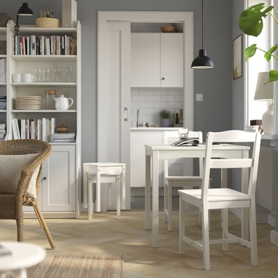Small kitchen with white HAUGA dining set and wooden storage.