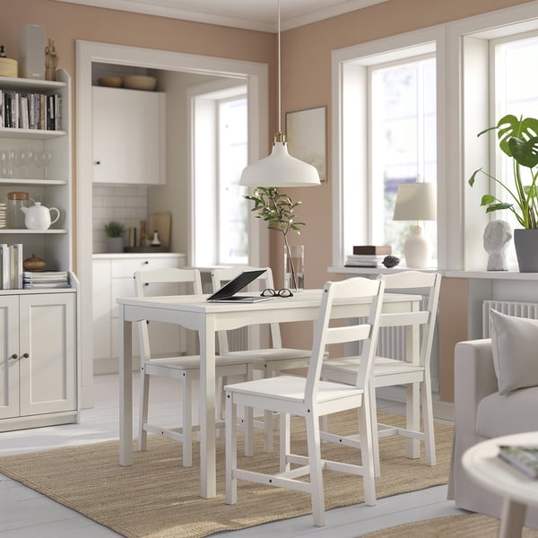 Bright, white 4-seat dining set with a square table and ladder-back chairs, placed on a jute rug, perfect for small spaces.
