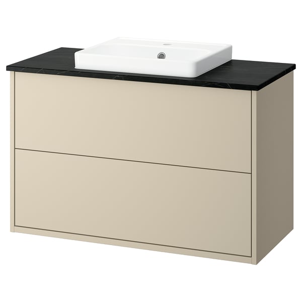 A beige HAVBÄCK bathroom cabinet with a black countertop and white square sink. It has two drawers for storage.