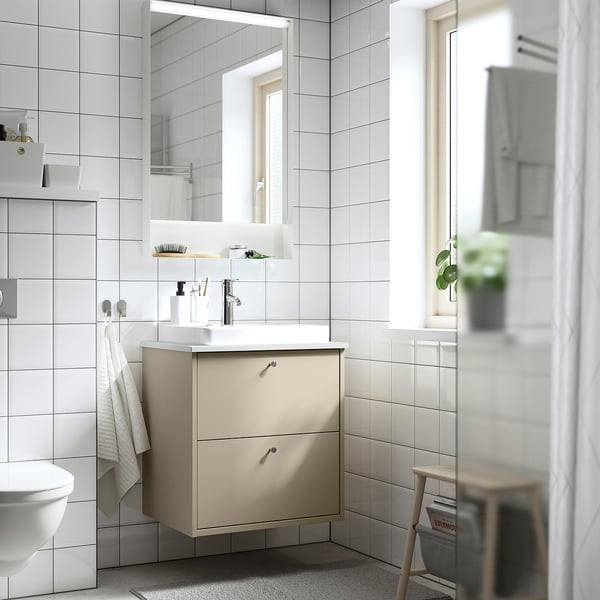 HAVBÄCK vanity: beige, wall-mounted with basin & drawers. White tiles, mirror, towels, stool.
