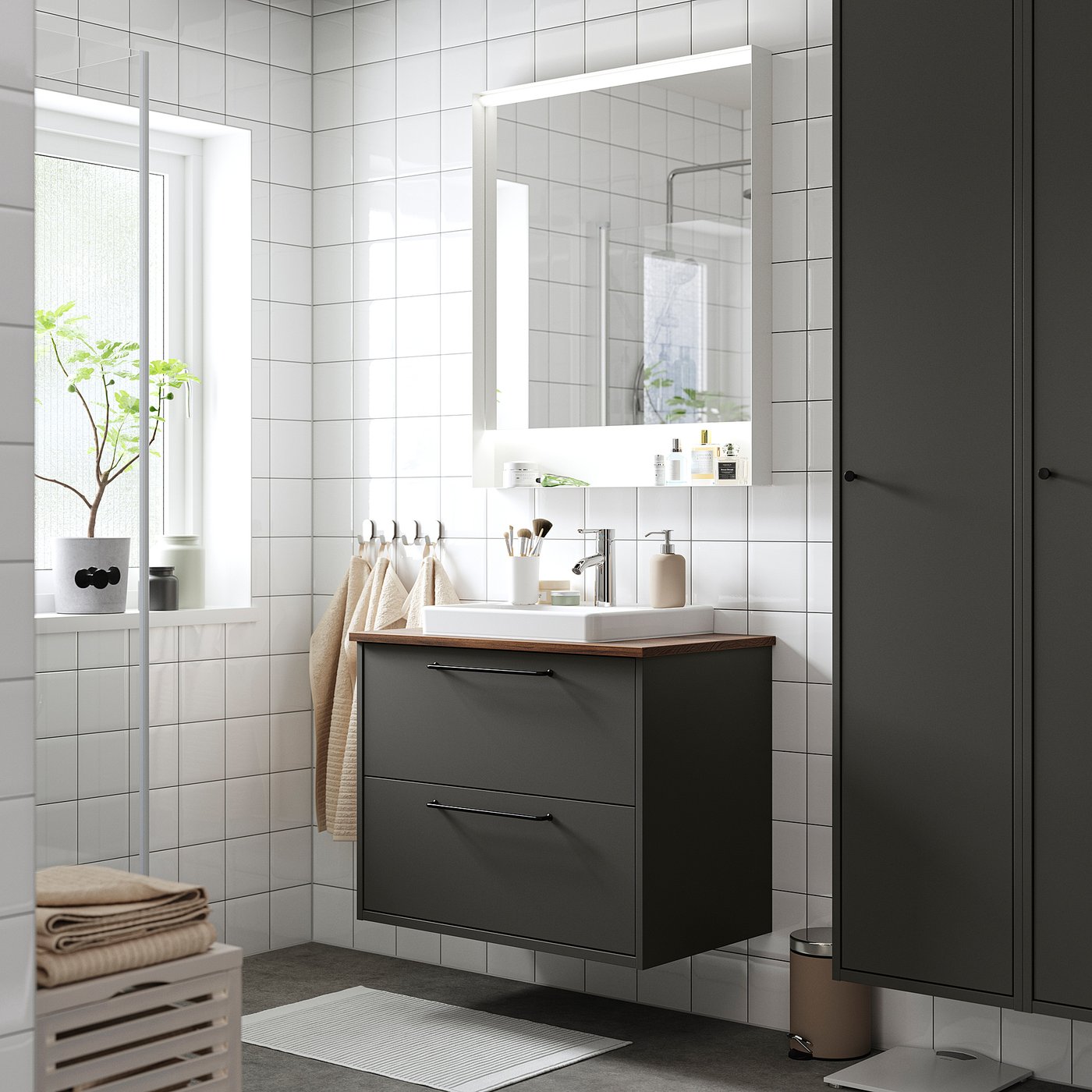 Modern bathroom with dark grey HAVBÄCK vanity, large mirror, white sink, clean design, and towels.