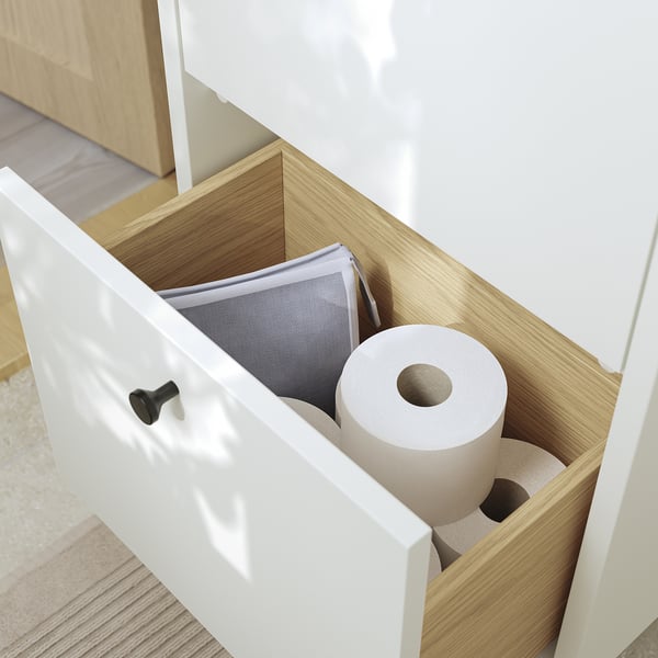 Open bathroom cabinet with toilet paper and accessories, showcasing storage space.