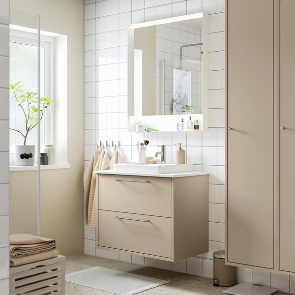 Minimalist bathroom with beige HAVBÄCK vanity, mirror, towels, plant.