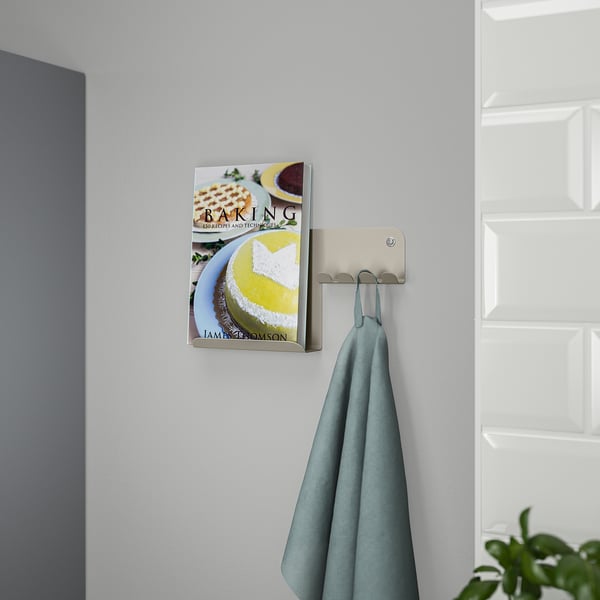 Wall-mounted organiser holds a cookbook and hangs a towel, ideal for kitchen use.