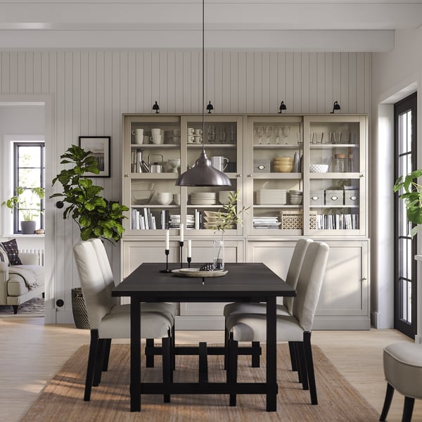 Minimalist dining area with HAVSTA sidesboard, table, chairs, lamp, plants, and glass cases.