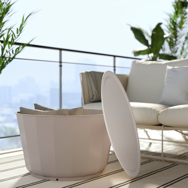 Modern outdoor sofa, beige, metal & mesh, deep seat, plush cushions, striped rug, glass railing, balcony view.