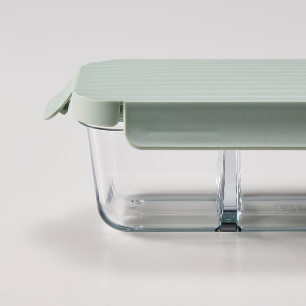 Glass lunch box with green lid, separated compartments for organised food storage.