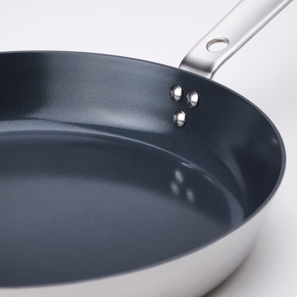 Close-up of a modern frying pan with sleek, dark non-stick interior and stylish silver handle.