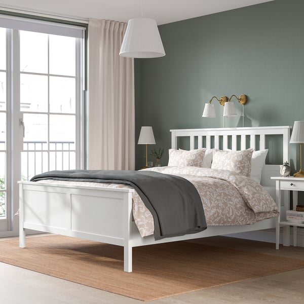 HEMNES white bed with ornate pattern and grey blanket against green walls.