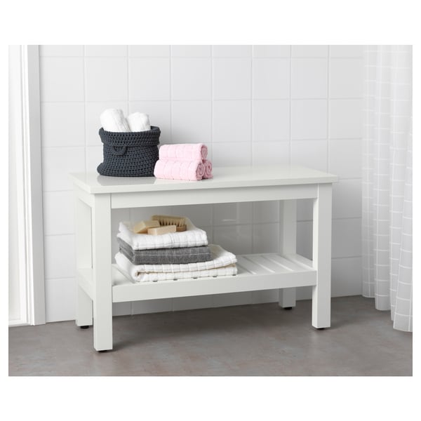 White HEMNES bathroom bench, knitted baskets with towels, concrete floor.