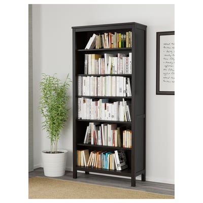 Bookshelf with various books and a plant, shown in a room.