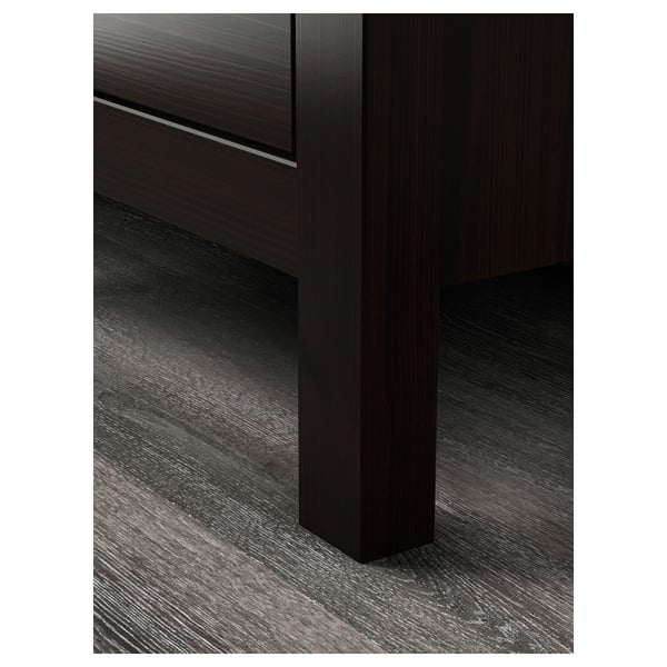 Dark wooden chest of drawers, seen from the corner, showcasing smooth, sturdy design and high-quality craftsmanship.