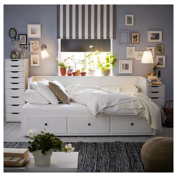 Cosy bedroom with white HEMNES day-bed, striped curtains, potted plants, and wall art. Light grey walls.