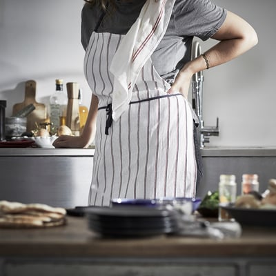 Person in kitchen with striped apron, counter with items.