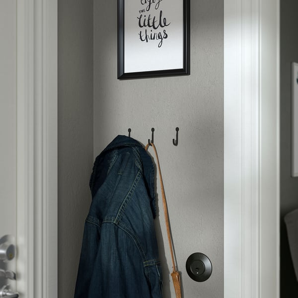 Three hooks holding denim jacket and belt; poster says enjoy the little things.